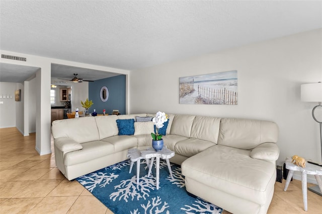 living room featuring a textured ceiling, tile patterned flooring, and ceiling fan