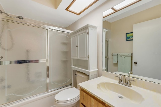 full bathroom with vanity, toilet, combined bath / shower with glass door, and a skylight