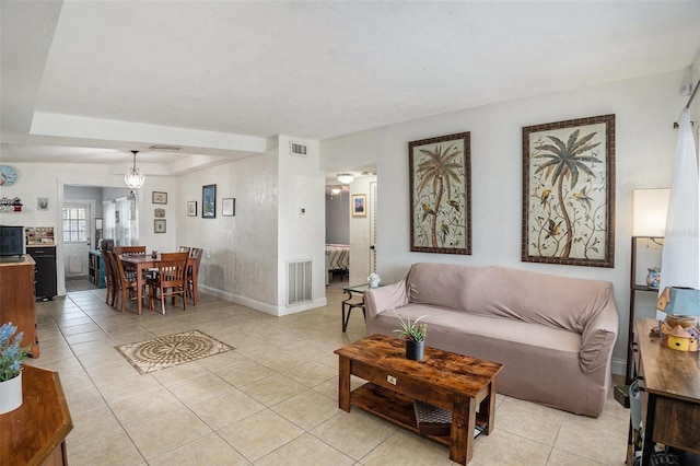 tiled living room featuring a chandelier and a raised ceiling