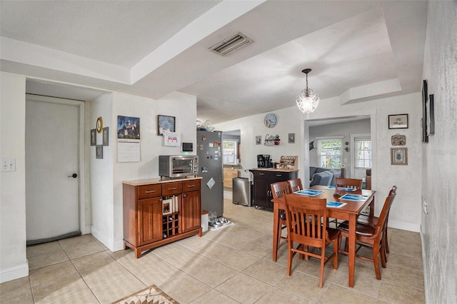 dining area featuring light tile patterned flooring and a raised ceiling