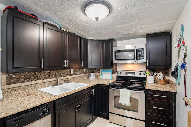 kitchen with stainless steel appliances, a textured ceiling, sink, light tile patterned floors, and light stone countertops