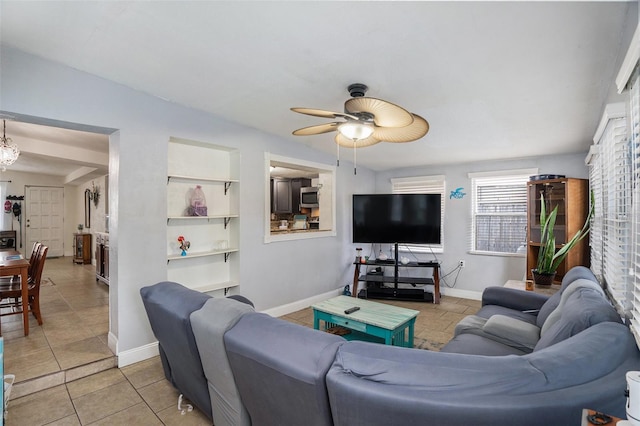 living room featuring built in shelves, ceiling fan, and light tile patterned flooring