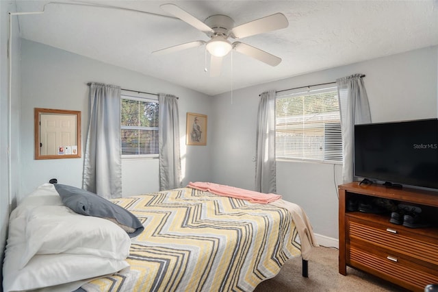 carpeted bedroom featuring multiple windows and ceiling fan