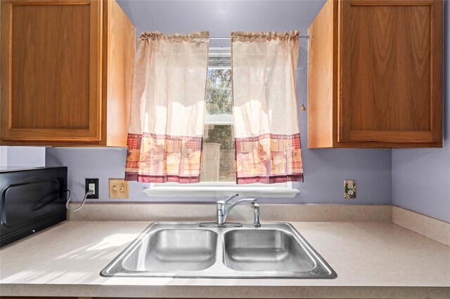 2102 Deltona Blvd, Spring Hill, FL 34606 - kitchen with a sink, light countertops, brown cabinets, and black microwave