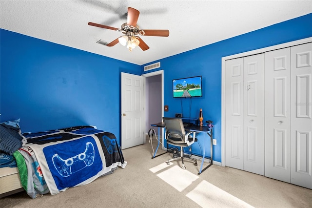 bedroom featuring ceiling fan, light colored carpet, a textured ceiling, and a closet