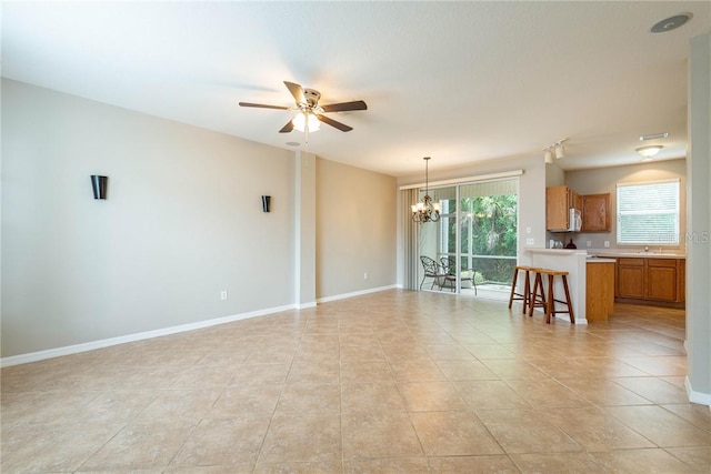 unfurnished living room featuring light tile patterned floors and ceiling fan with notable chandelier