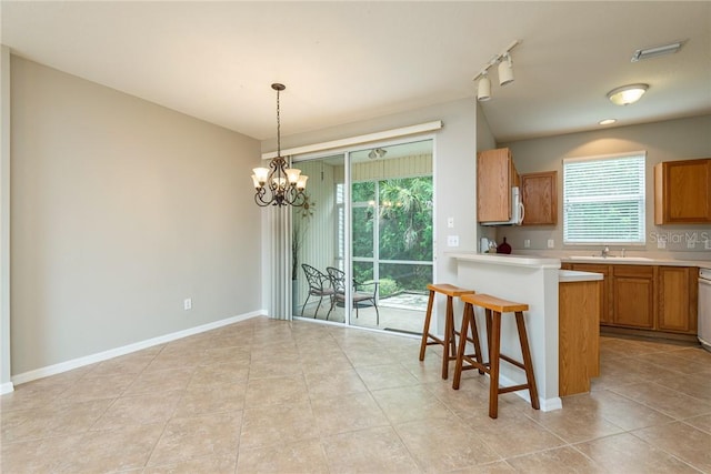 kitchen featuring a notable chandelier, a kitchen breakfast bar, a healthy amount of sunlight, and rail lighting