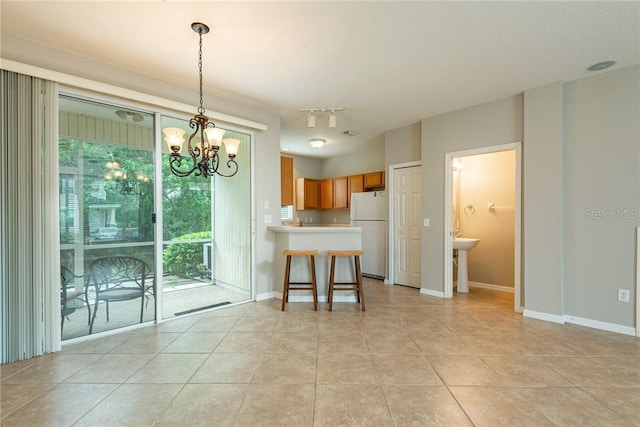 kitchen with kitchen peninsula, a wealth of natural light, white fridge, and hanging light fixtures