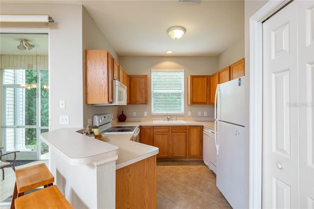 kitchen featuring kitchen peninsula, white appliances, sink, and a wealth of natural light