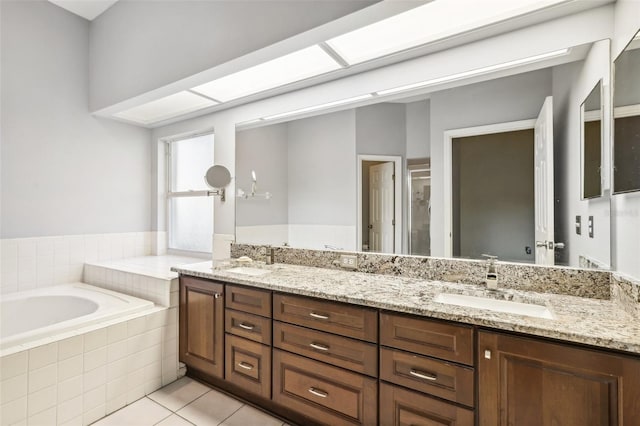 bathroom with tile patterned flooring, vanity, and a relaxing tiled tub