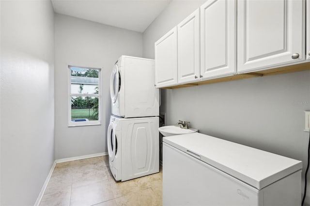 laundry room featuring cabinets, light tile patterned floors, sink, and stacked washer and clothes dryer