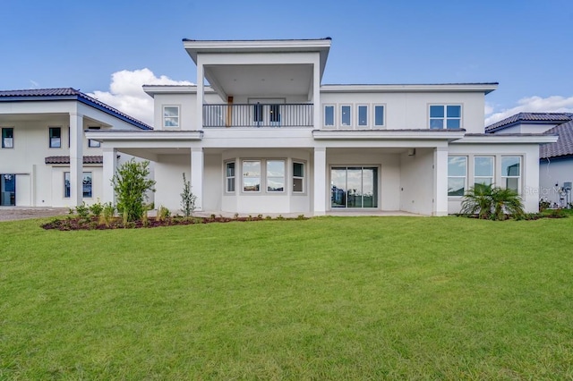 back of property with a yard and a balcony