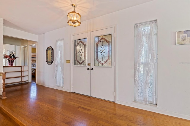 entrance foyer with an inviting chandelier, wood-type flooring, and french doors