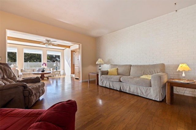 living room with brick wall, hardwood / wood-style floors, and ceiling fan