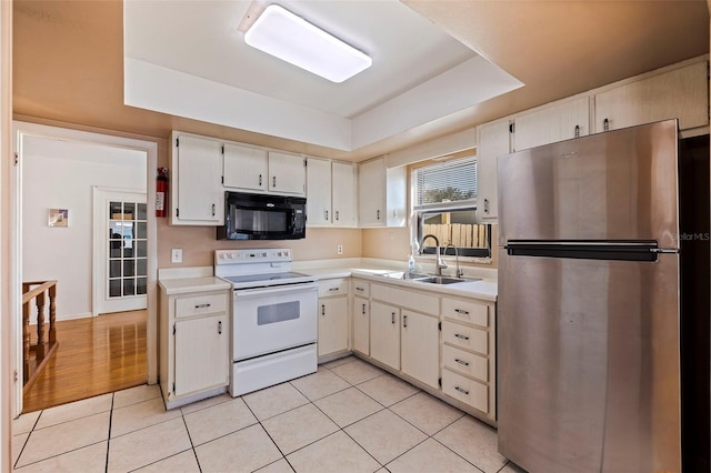 kitchen featuring sink, white electric range oven, a raised ceiling, light wood-type flooring, and stainless steel fridge