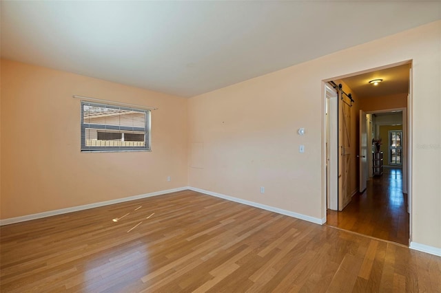 empty room with a barn door and light hardwood / wood-style floors