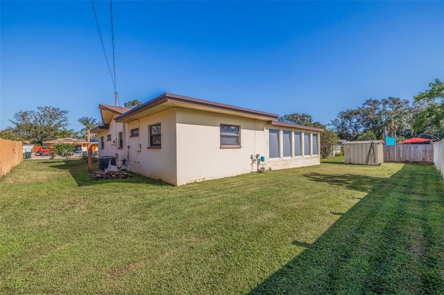 rear view of house featuring a lawn and a shed