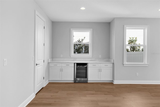 bar featuring a wealth of natural light, light wood-type flooring, white cabinetry, and beverage cooler