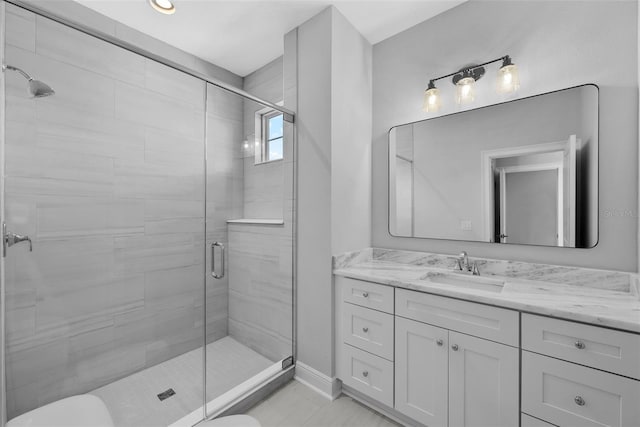 bathroom featuring a shower with door, vanity, and toilet