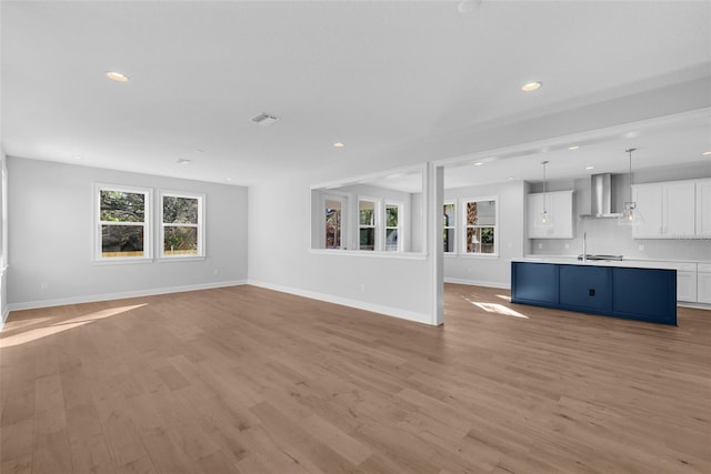 unfurnished living room with light hardwood / wood-style flooring and sink