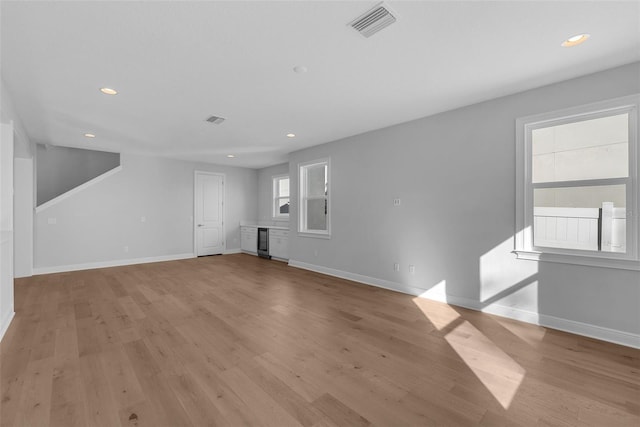 unfurnished living room with wine cooler and light hardwood / wood-style flooring