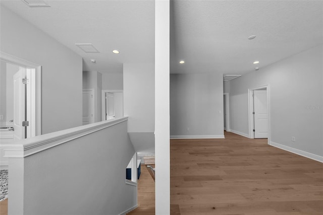 corridor featuring a textured ceiling and light hardwood / wood-style flooring