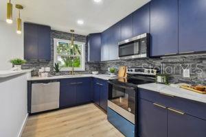 kitchen featuring stainless steel appliances, blue cabinetry, decorative light fixtures, and backsplash