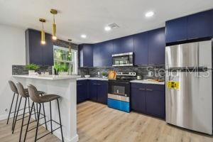 kitchen featuring kitchen peninsula, appliances with stainless steel finishes, hanging light fixtures, light hardwood / wood-style flooring, and blue cabinets