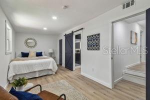 bedroom featuring a barn door and light hardwood / wood-style floors