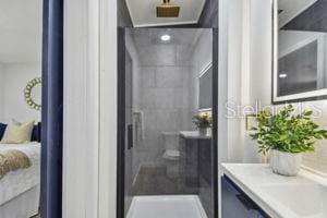 bathroom with tiled shower and vanity