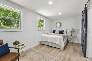 bedroom with a barn door and light hardwood / wood-style flooring