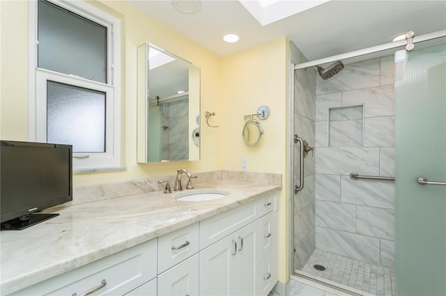 bathroom with a skylight, vanity, and an enclosed shower