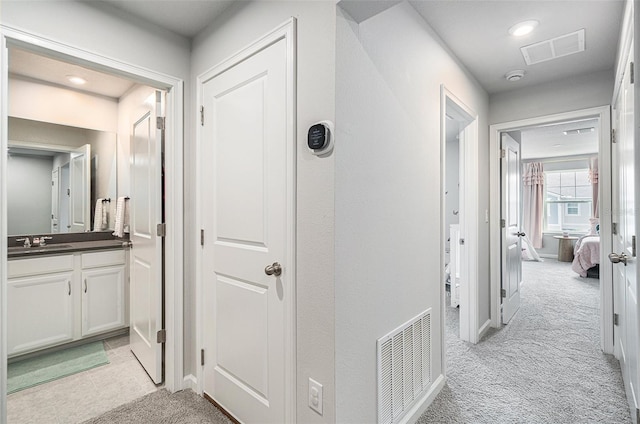 corridor with light carpet and sink