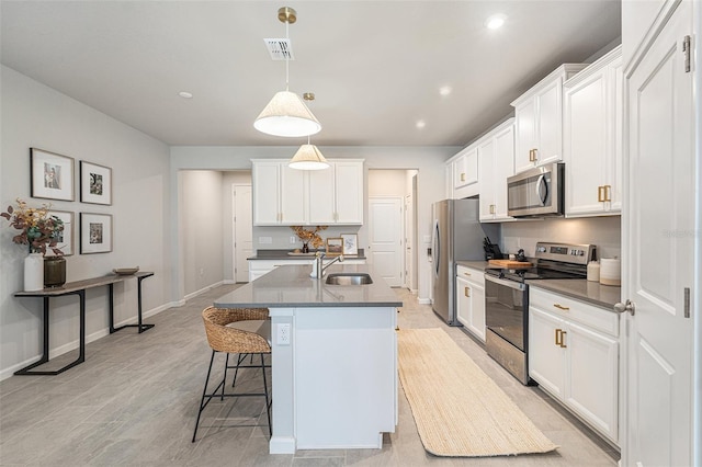 kitchen with sink, white cabinetry, stainless steel appliances, a center island with sink, and decorative light fixtures