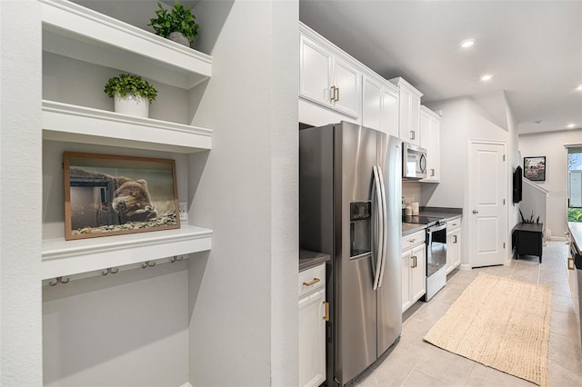 kitchen with stainless steel appliances, light tile patterned flooring, and white cabinets