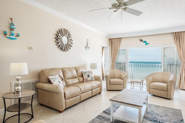 living room featuring a water view, ornamental molding, ceiling fan, a textured ceiling, and light tile patterned floors