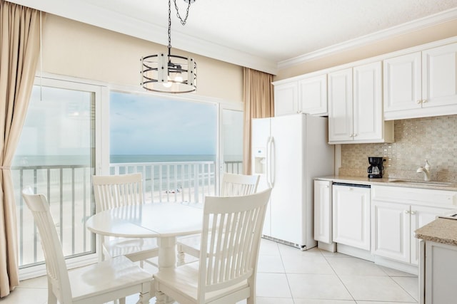 kitchen featuring white cabinets, sink, ornamental molding, white fridge with ice dispenser, and pendant lighting