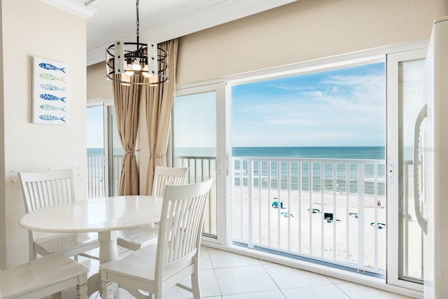 dining area featuring a view of the beach, a wealth of natural light, a water view, and a chandelier