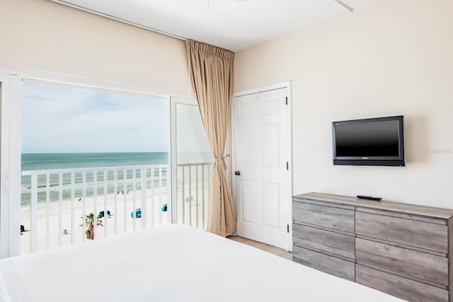 unfurnished bedroom featuring light wood-type flooring, a water view, and a view of the beach