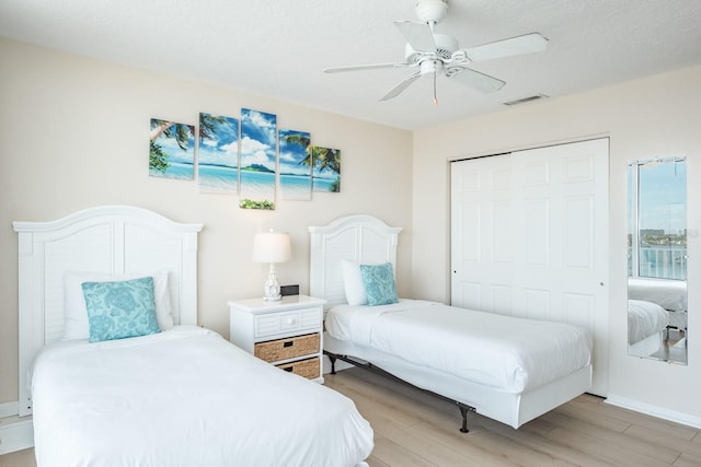 bedroom with ceiling fan, a textured ceiling, a closet, and light hardwood / wood-style flooring