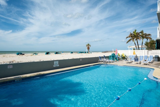 view of swimming pool with a patio area, a view of the beach, and a water view