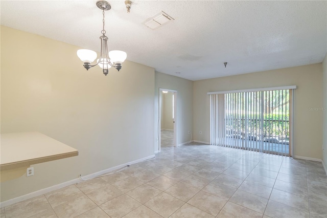 empty room with a textured ceiling, light tile patterned floors, and a notable chandelier