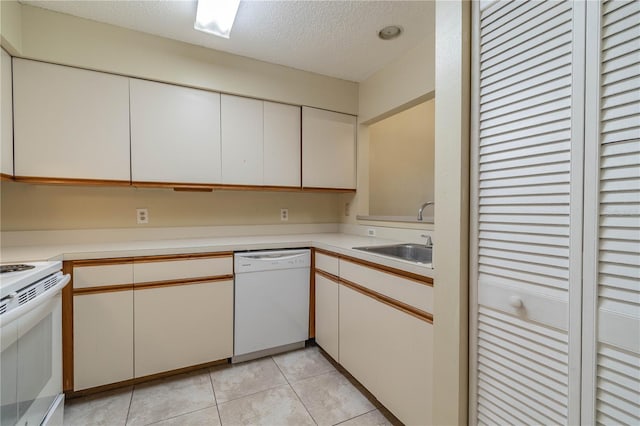 kitchen with white appliances, white cabinetry, sink, and a textured ceiling