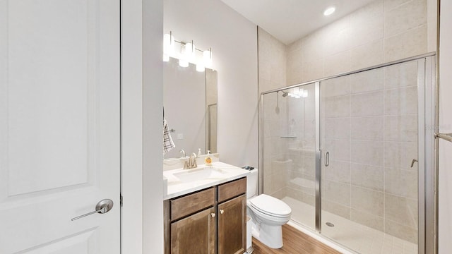 bathroom with vanity, toilet, a shower with shower door, and hardwood / wood-style floors