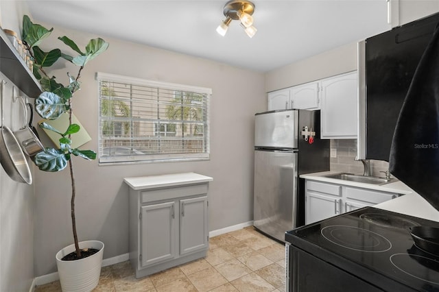 kitchen with decorative backsplash, stainless steel fridge, sink, electric range, and white cabinets