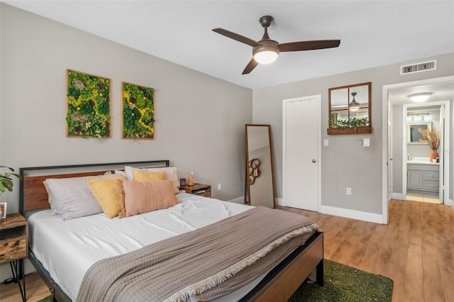 bedroom featuring ceiling fan, light hardwood / wood-style floors, and ensuite bath