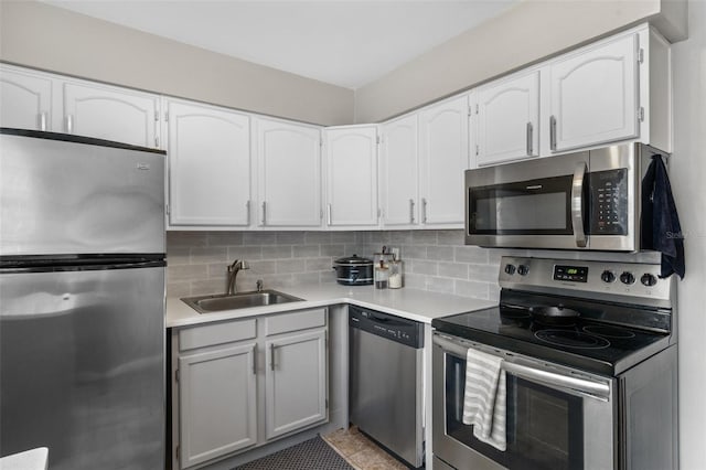 kitchen with decorative backsplash, white cabinetry, sink, and appliances with stainless steel finishes