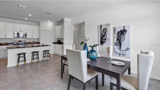 dining space with a textured ceiling and light tile patterned floors