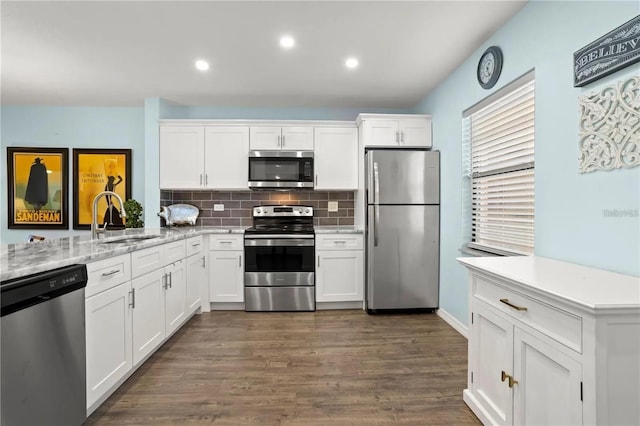 kitchen featuring light stone countertops, white cabinetry, sink, stainless steel appliances, and dark hardwood / wood-style flooring