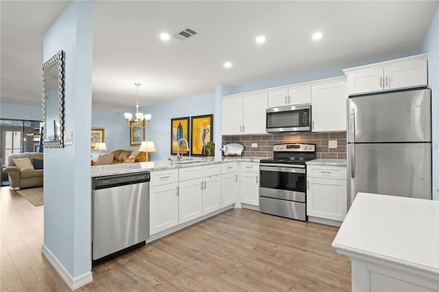 kitchen with pendant lighting, light wood-type flooring, white cabinetry, and stainless steel appliances